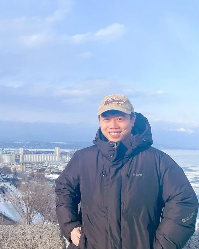Truong Thanh Hung Nguyen smiling on a winter day above the frozen St. Lawrence River in Québec City